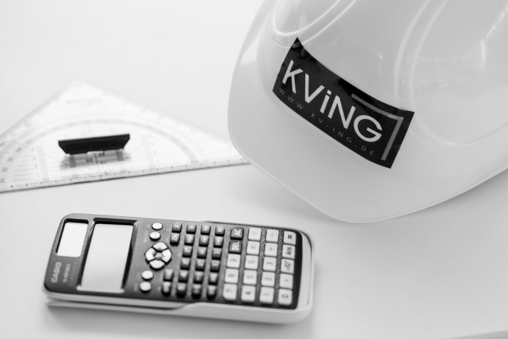 Bild zeigt Taschenrechner, Geodreieck und Bauhelm mit KV Aufdruck